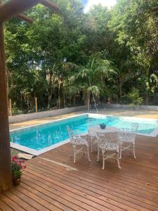 eine Terrasse mit einem Tisch und Stühlen neben einem Pool in der Unterkunft Casa 05 suítes, piscina e natureza in Mata de Sao Joao
