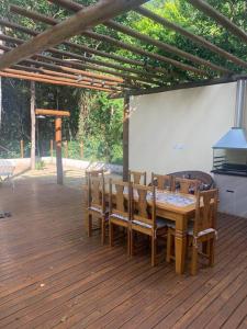 a wooden table and chairs on a wooden deck at Casa 05 suítes, piscina e natureza in Mata de Sao Joao