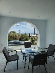 una camera con un tavolo in vetro, sedie e una finestra di Αegean Εyes a Città di Tinos
