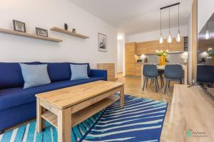uma sala de estar com um sofá azul e uma mesa em Apartament Gambit, Ogrody Pieniawskie, MyWeek em Polanica-Zdrój