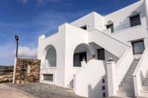 Casa blanca con ventanas grandes y escaleras en Αegean Εyes en Tinos Town