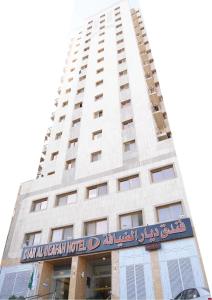 a tall white building with a sign in front of it at Diyar Al Deafah Hotel in Mecca