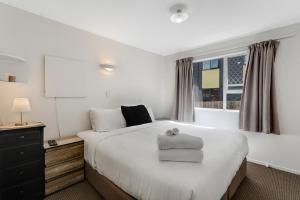 Un dormitorio con una gran cama blanca y una ventana en Homespun Unit with deck, air-con and parking en Auckland