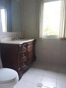 a bathroom with a toilet and a sink and a window at Coral Harbour Beach Apartment in Nassau