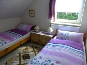 - 2 lits dans une petite chambre avec des draps violets dans l'établissement Ferienwohnung, à Tecklembourg