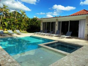 einen Pool mit Liegestühlen neben einem Haus in der Unterkunft Seasideserenity Luxury Villa Steps From The Beach in La Romana