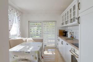 a kitchen with white cabinets and a table in it at VacationClub - Ochorowicza 3E VacationHome in Wisła