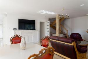 ein Wohnzimmer mit einem Tisch, Stühlen und einem TV in der Unterkunft VacationClub - Ochorowicza 3E VacationHome in Wisła