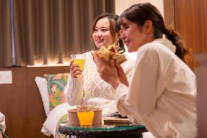 Dos mujeres sentadas en una mesa comiendo pizza en Aqua Resort in Chatan, en Chatan