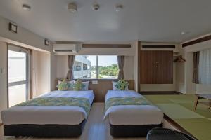 two beds in a room with a window at Aqua Resort in Chatan in Chatan