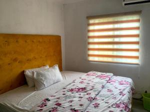 a bedroom with a bed with a floral bedspread and a window at New Travellers Lodge Sangotedo Lagos in Lekki