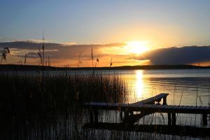 a bench sitting next to a lake with the sunset at Ralph's Haus am See in Plau am See