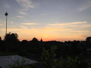 una puesta de sol sobre una ciudad con una iglesia a lo lejos en Ferienhaus Eifeltraum Magma en Berlingen
