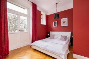 ein rotes Schlafzimmer mit einem Bett und einem Fenster in der Unterkunft Luxury Apartment with Two Bedrooms and Balcony by Renters Prestige in Krakau