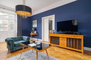a living room with a tv and a blue wall at Luxury Apartment with Two Bedrooms and Balcony by Renters Prestige in Kraków