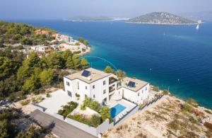 an aerial view of a house on a hill next to the water at Villa Palm Bay 2, heated pool - 10 m from the sea in Ražanj