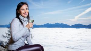 Chalet Petit في Kanzelhöhe: امرأة جالسة في الثلج تحمل كأس من النبيذ