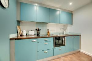 uma cozinha com armários azuis e um lavatório em All Saints Apartments 606 by Week2Week em Newcastle upon Tyne