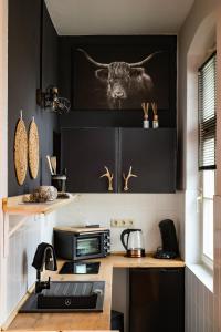 a kitchen with black cabinets and a sink with a cow on the wall at Finken Lodge in Buckow