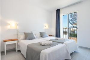 two beds in a room with a large window at Vibra Caleta Playa Apartmentos-3SUP in Sa Caleta
