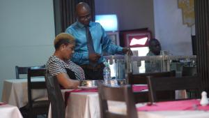 a man standing next to a woman sitting at a table at Oakspring Hotel and Luxury Suites in Lagos