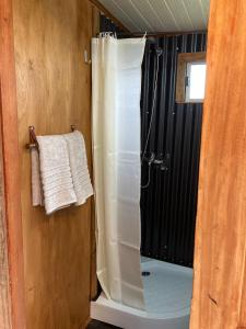 a shower with a white shower curtain in a bathroom at La Casita in Tacuarembó