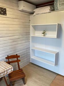 Cette chambre dispose d'étagères blanches et d'une chaise en bois. dans l'établissement La Casita, à Tacuarembó