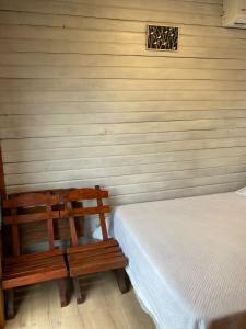 a bedroom with two wooden benches and a bed at La Casita in Tacuarembó