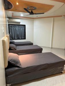 een kamer met 3 bedden en een plafondventilator bij Beyond Stays in Pune