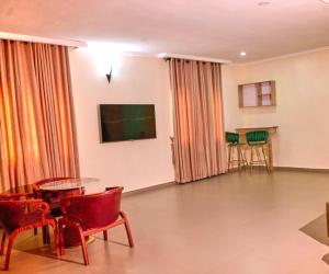 a living room with red chairs and a flat screen tv at Bosanic Hotel in Benin City