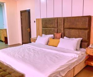 uma cama grande com lençóis brancos e almofadas em Bosanic Hotel em Benin City