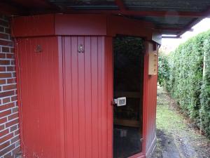 un retrete rojo con una puerta roja en un edificio en BlüteNo1 mit Sauna, Kamin und Garten, en Wiesmoor