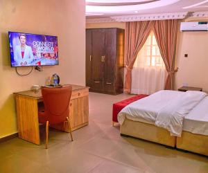 um quarto com uma cama e uma televisão na parede em Bosanic Hotel em Benin City