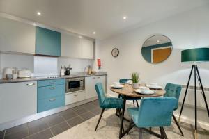 a kitchen with a table and blue chairs in a kitchen at All Saints Apartments 406 by Week2Week in Newcastle upon Tyne