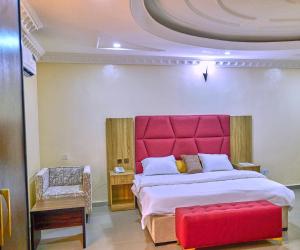 a bedroom with a large bed with a red headboard at Bosanic Hotel in Benin City
