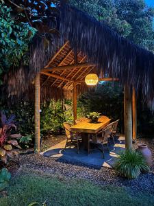 a wooden table and chairs under a thatched roof at Aldeia dos Corais - Taipu de Fora in Barra Grande