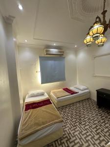 two beds in a room with a window and a chandelier at فندق البديل in Al Madinah