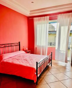 ein rotes Schlafzimmer mit einem Bett und einem Fenster in der Unterkunft Napoli Sea View in Portici