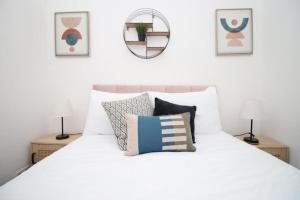 a bedroom with a white bed with pillows and a mirror at Peaceful 3 Bed Flat with Parking and Balcony by CTO Serviced Apartments in Cardiff
