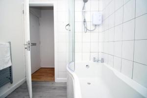 biała łazienka z wanną i prysznicem w obiekcie Peaceful 3 Bed Flat with Parking and Balcony by CTO Serviced Apartments w Cardiff