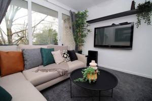 a living room with a couch and a tv on a wall at Peaceful 3 Bed Flat with Parking and Balcony by CTO Serviced Apartments in Cardiff