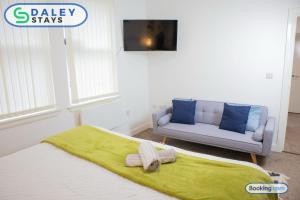 een slaapkamer met een bed, een bank en een tv bij Manchester Apartment with Free Gated Parking by Daley Stays in Manchester