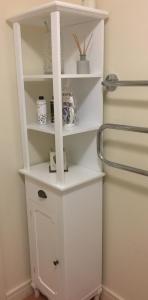 a white shelf in the corner of a bathroom at Moonbay apartment in Cardiff