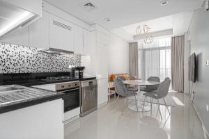 cocina con armarios blancos, mesa y sillas en ALH Vacay - Aykon City 2 Tower C - 2 bedrooms, en Dubái