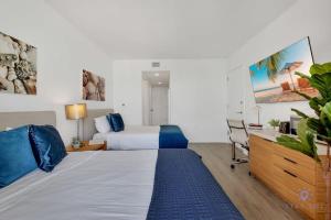 a hotel room with a bed and a desk and a bed at Infinite Views Amazing Pool Gym in Hallandale Beach