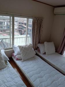 two beds in a room with a large window at Tokyo downtown芍藥莊 in Tokyo
