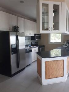 a kitchen with white cabinets and a stainless steel refrigerator at Oceanview at Coral Habour in Nassau