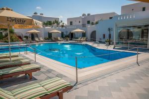 a large swimming pool with lounge chairs in front of a hotel at Astir Of Naxos in Naxos Chora