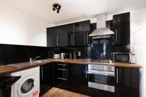 a kitchen with black cabinets and a washing machine at 2 bed Bethnal Green Penthouse in London