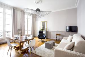 a living room with a couch and a table and chairs at Appartement Caumartin Lafayette in Paris
